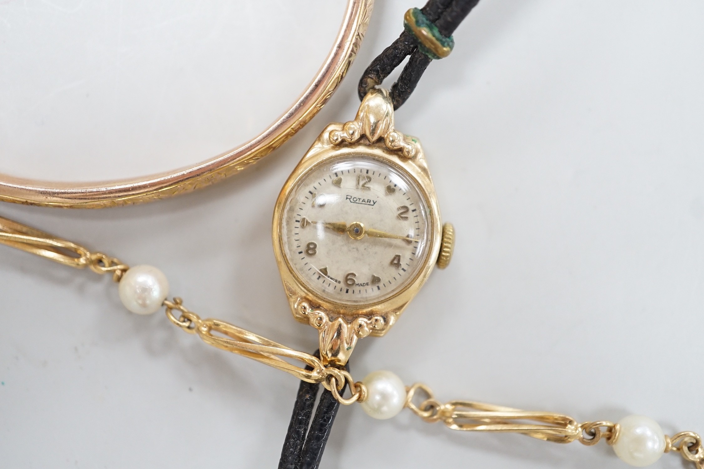 A modern 9ct gold and cultured pearl set bracelet, 18.5cm, a 9ct gold hinged bangle and a lady's yellow metal Rotary wrist watch, gross weight 21.3 grams.